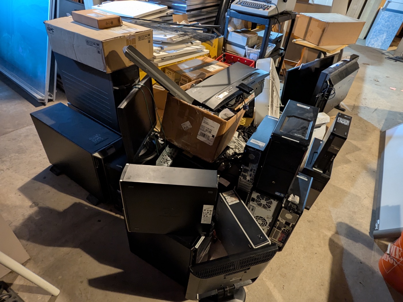 Mixed retired computers, monitors, boxes, and IT equipment staged for pickup