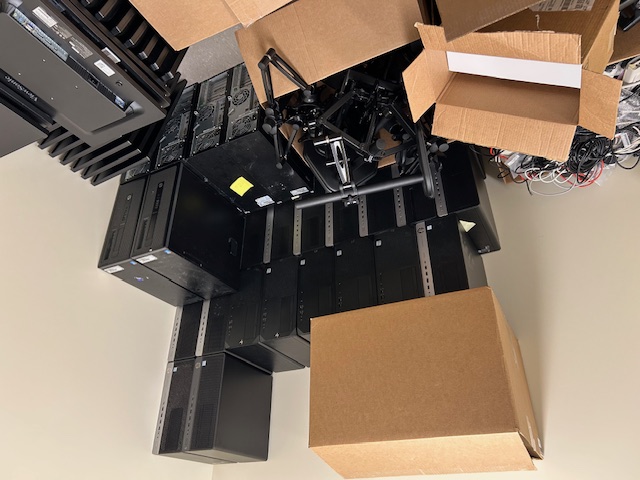 Stock room stacked with retired desktop computers, cables, and equipment boxes