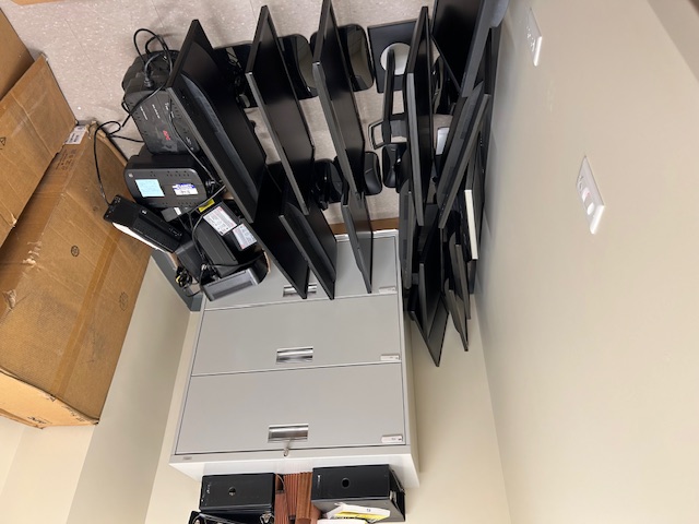 Small storage room with retired monitors, screens, and office equipment